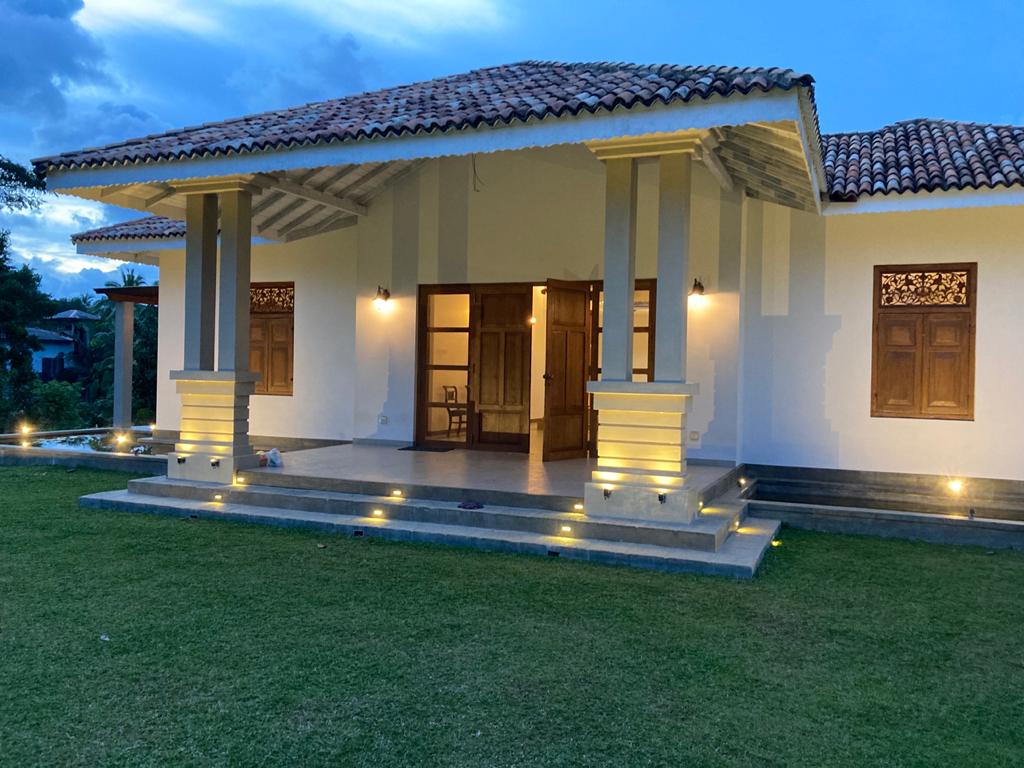 White villa with timber doors and a tiled roof illuminated at dusk