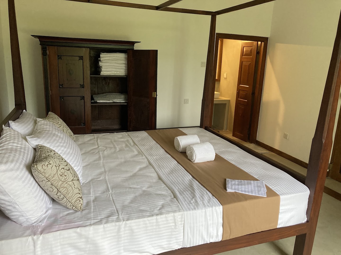 Bedroom with a wide timber bed, fresh linen, and ensuite doorway