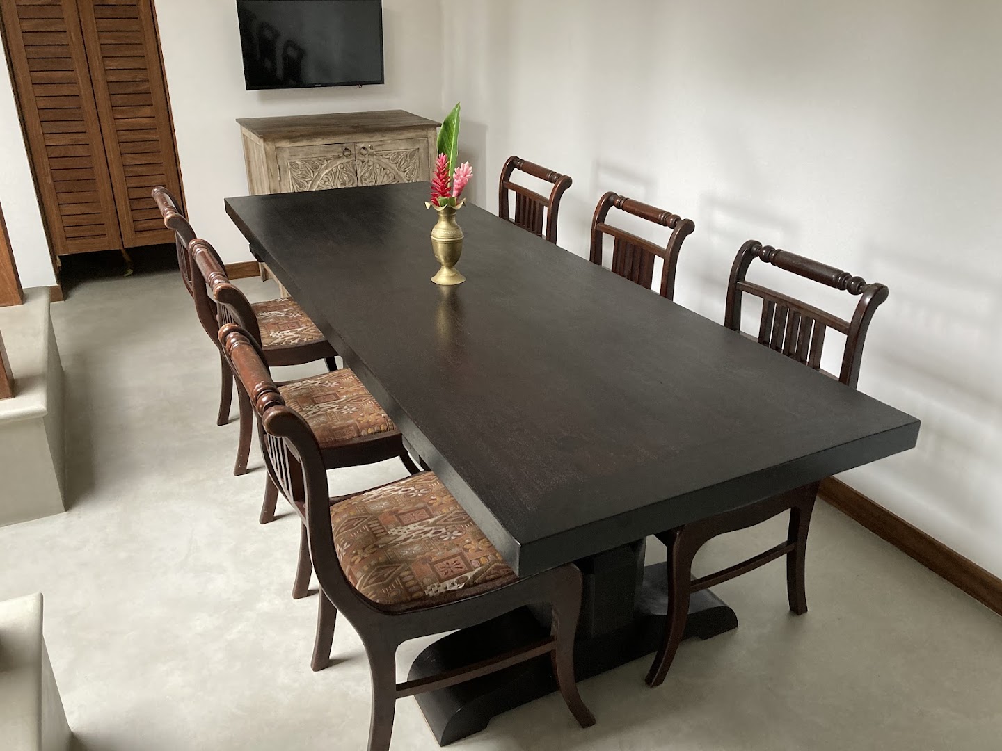 Long indoor dining table with timber chairs and fresh flowers