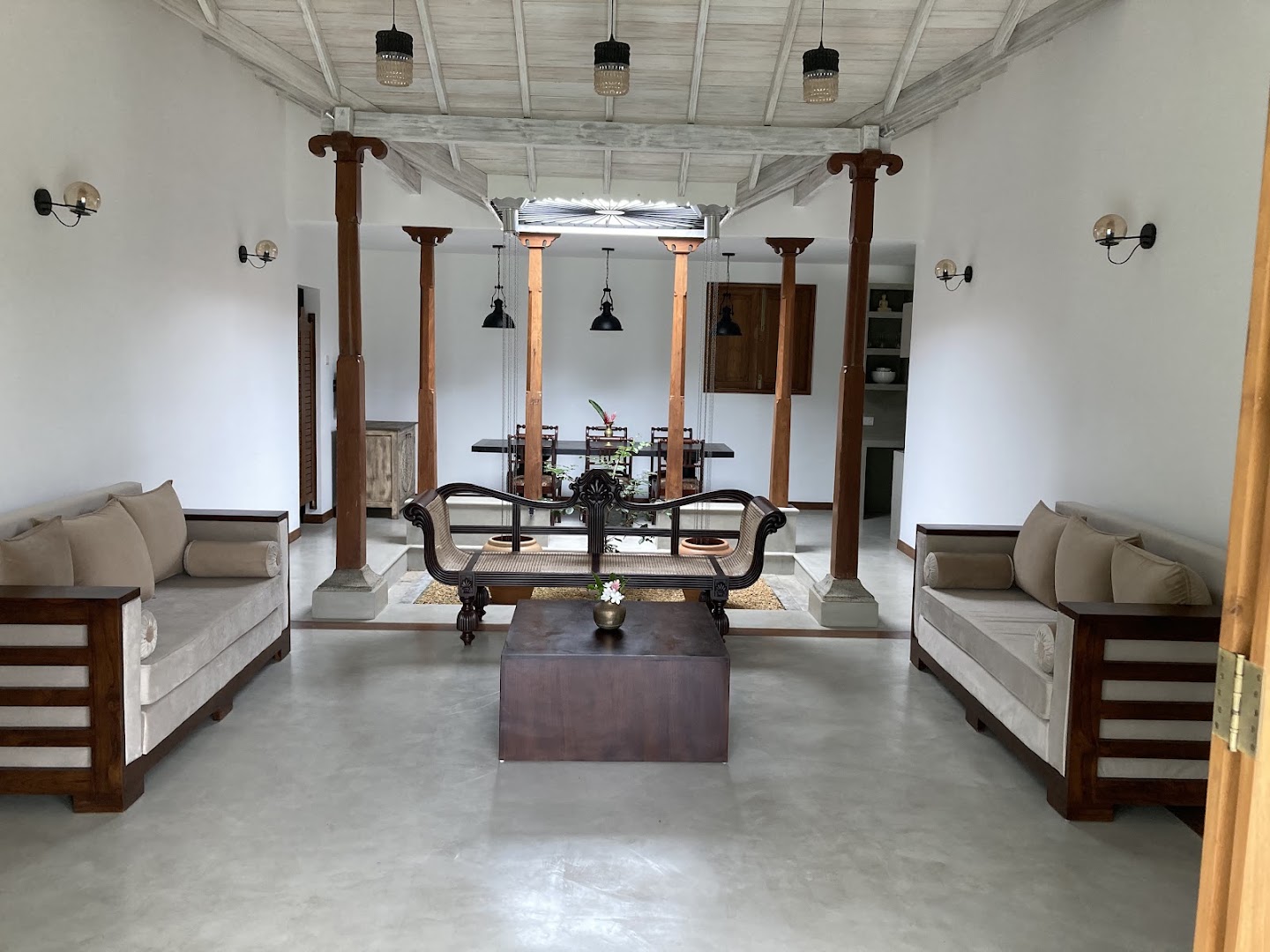 Open living room with timber columns, pale seating, and a central indoor garden